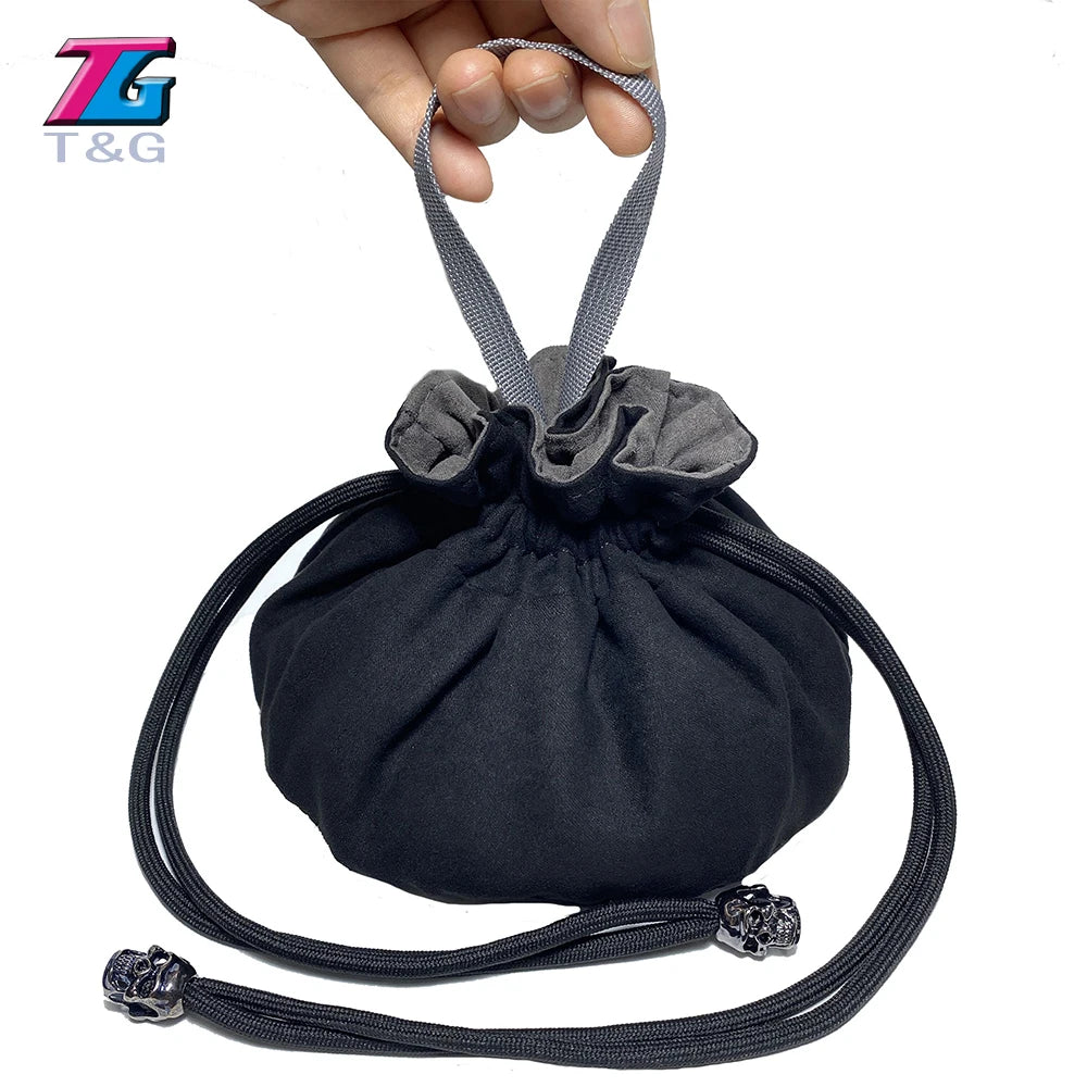 A black velvet dice storage pouch with a drawstring is held by a hand.