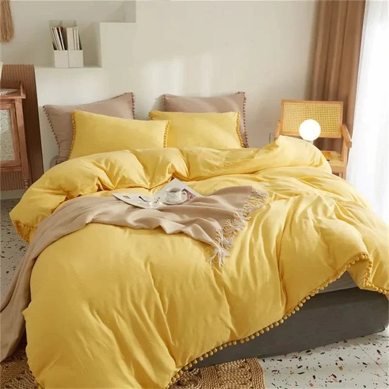 A bright yellow duvet cover set with soft microfiber bedding and pom tassels on a bed.