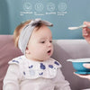 A baby wearing a light gray cotton gauze bib while sitting on a couch, with product features listed above.