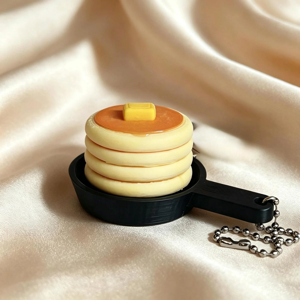 A stack of round, layered silicone or plastic discs in yellow and orange rests on a black keychain.