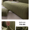 A textured olive green quilted stretch sofa cover draped on a sofa, showing the woven pattern and fabric detail.