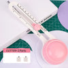A white adjustable circular paper cutter tool with a pink blade and measuring markings is shown on a green surface.