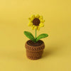 Handcrafted crochet sunflower with green leaves growing in a brown woven pot