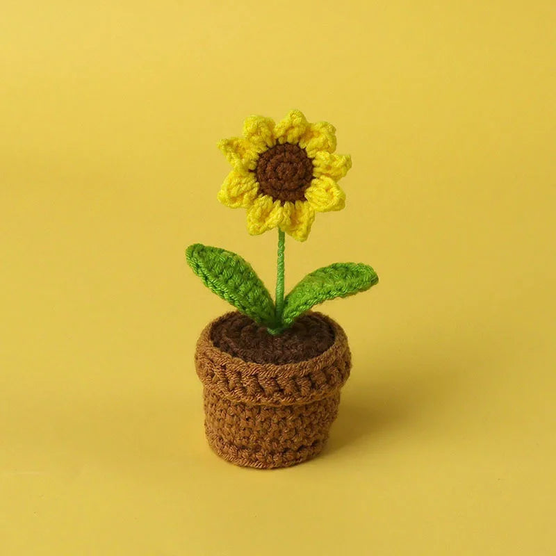 Handcrafted crochet sunflower with green leaves growing in a brown woven pot
