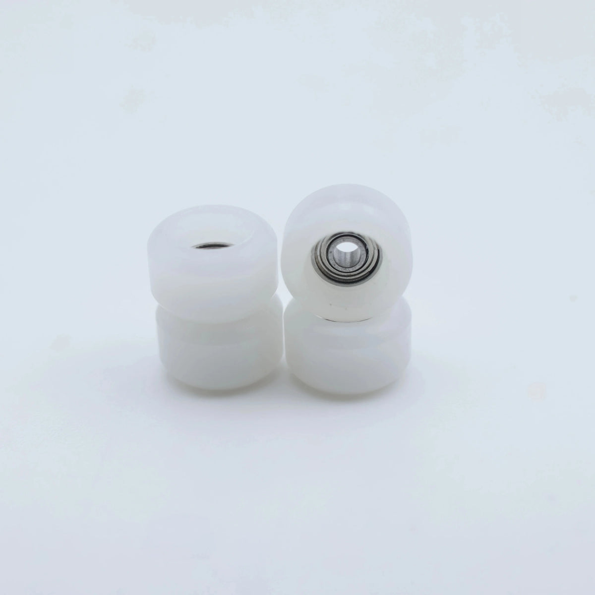 Two white urethane fingerboard wheels with visible bearings