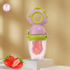 A pink and green rotating silicone baby fruit feeder with a dinosaur design, holding strawberries.