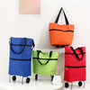 A collection of colorful foldable rolling shopping bags in blue, orange, and red displayed on a white shelf.
