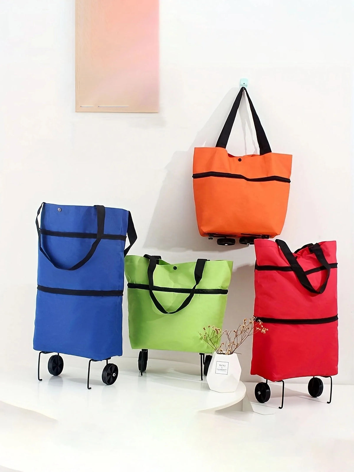 A collection of colorful foldable rolling shopping bags in blue, orange, and red displayed on a white shelf.