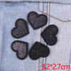A set of five black and silver glitter heart iron-on embroidered patches on a denim fabric.