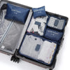 A gray travel packing cube case filled with six blue and white fabric laundry pouches.