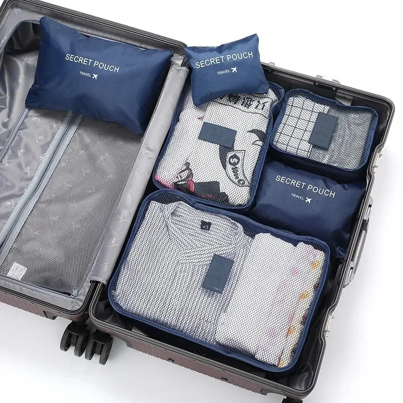 A gray travel packing cube case filled with six blue and white fabric laundry pouches.