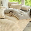 A beige and cream gingham duvet cover set with two pillows on a bed near a window.