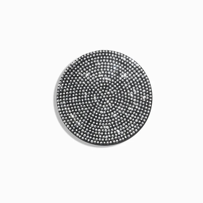 A circular coaster made of small, shiny, silver-toned studs or diamonds.