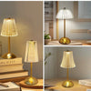 A gold-toned crystal touch table lamp with a translucent shade illuminates a wooden surface.