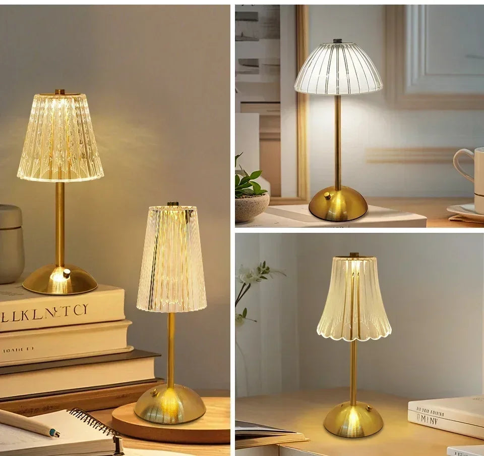 A gold-toned crystal touch table lamp with a translucent shade illuminates a wooden surface.