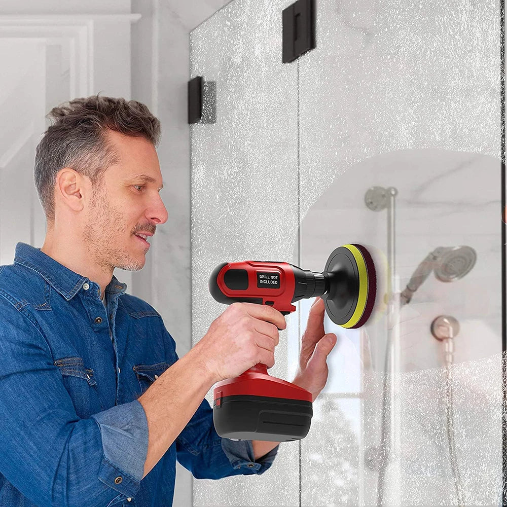 A man is using a red and black drill brush cleaning kit on a glass surface for detailing.