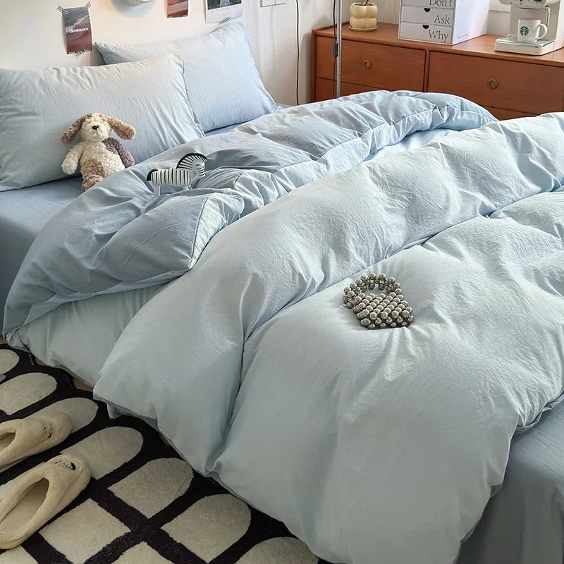 A light blue ultra-soft washed cotton duvet cover set with a matching duvet and pillows on a bed.