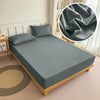 A fitted bed sheet in solid gray is displayed on a bed, with a close-up showing the fabric texture.