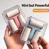A hand holds a clear plastic container of a mini lint roller with pink and light blue rollers.