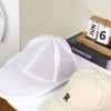 A white mesh laundry bag for hats and delicate clothing is shown next to a beige cap.