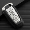 A silver TPU leather car key cover with multiple buttons rests on a dark textured surface.