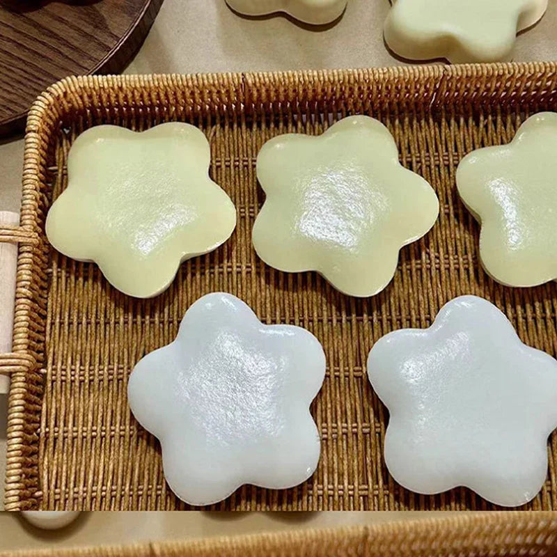 A collection of soft, squeezable star-shaped stress relief toys in pale yellow and white are arranged in a woven basket.
