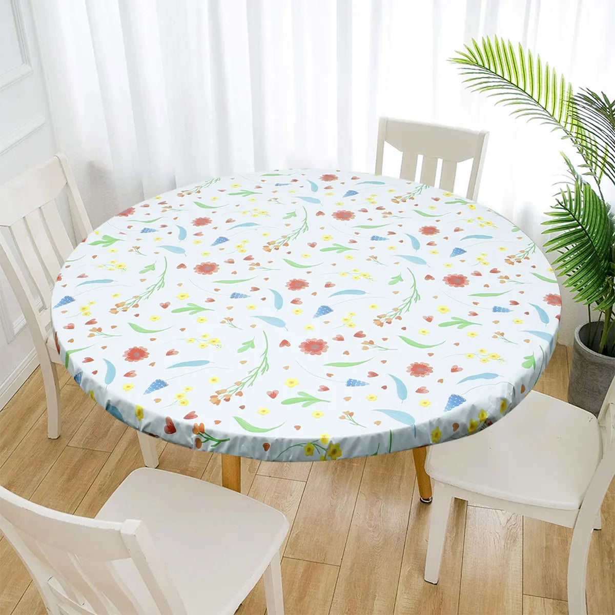 A white round tablecloth with a floral pattern is displayed on a table surrounded by white chairs.