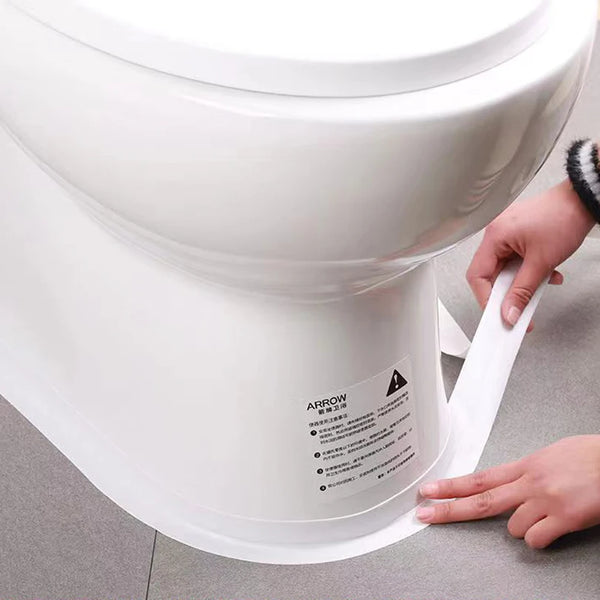 A hand is applying waterproof self-adhesive sealing tape to the base of a white ceramic toilet bowl.