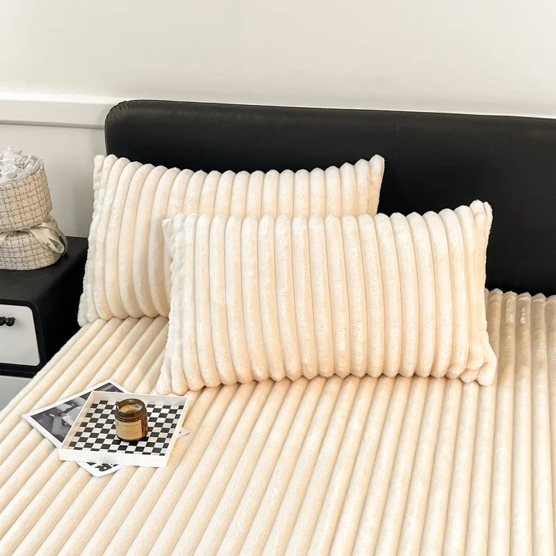 A close-up of a thick, cream-colored knit fitted bed sheet with vertical ribbing resting on a bed.