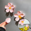 Pink sakura flower magnetic bag sealer clips casting shadows on a gray surface.