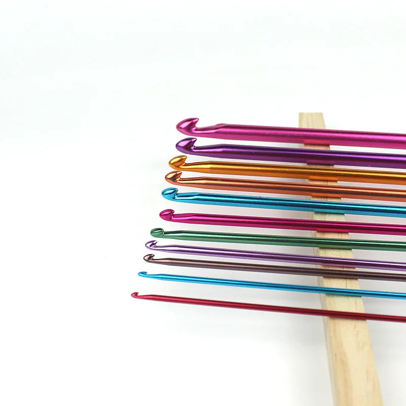 A set of 23 colorful Tunisian crochet hooks with bamboo cables arranged in a row.