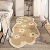 A beige irregular area rug with a subtle floral pattern lies on a light wood floor next to a bed.