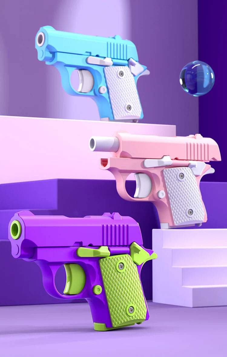 Three brightly colored mini 3D printed gravity fidget pistols displayed on purple and pink tiered platforms.