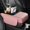 Pink quilted car armrest cushion with storage and cup holders placed on a black car seat.