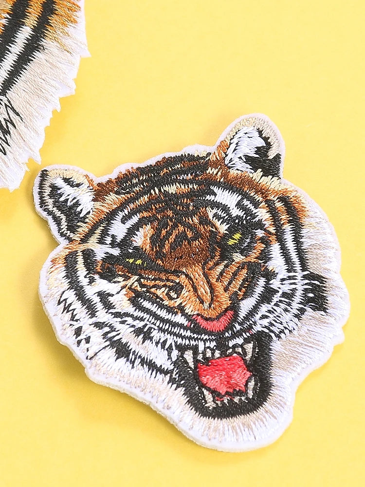 A detailed embroidery patch depicting a tiger's face in black, white, and orange tones.