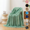 A teal brushed flannel throw blanket draped over a chair in a bright room.