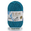 A skein of teal blue milk cotton blend yarn with a label featuring a dog and text in Chinese and English.
