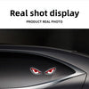 Close-up of a red demon eye LED decal applied to the side window of a dark car.