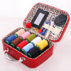 A red portable faux leather sewing kit box containing various colored threads and a needle organizer.