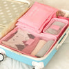 A pink packing cube set with six pieces is shown inside a light blue storage box.
