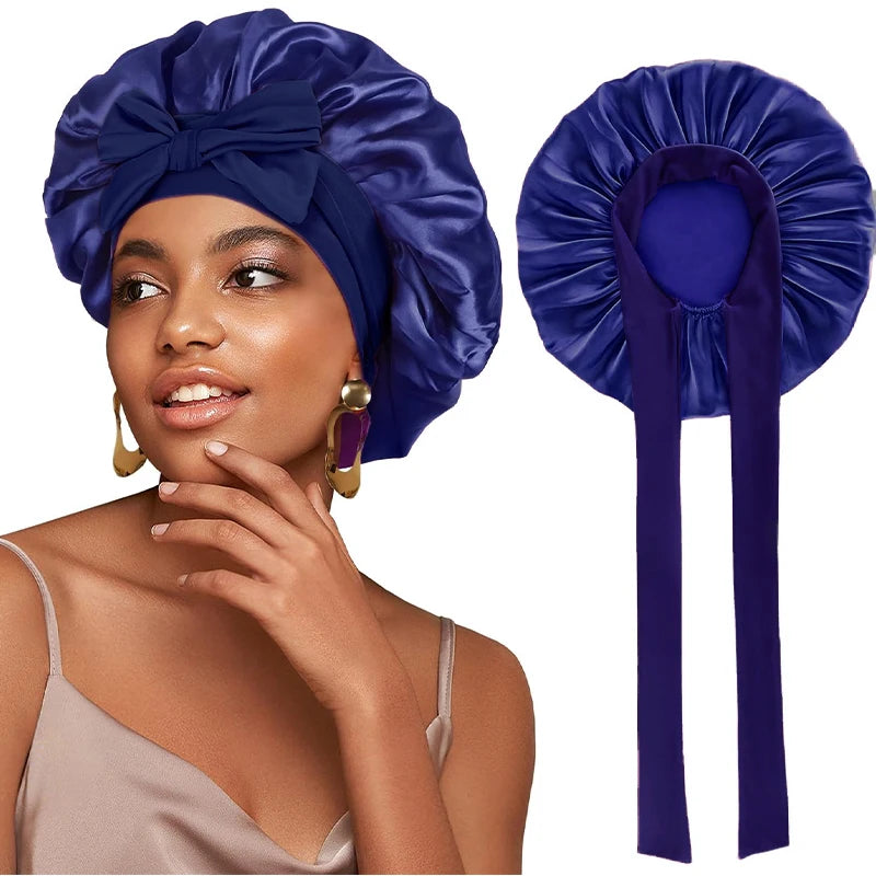 A woman wearing a royal blue satin sleeping bonnet with an adjustable tie.