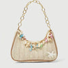 A beige woven straw shoulder bag with gold chain strap and colorful ocean shell charms.
