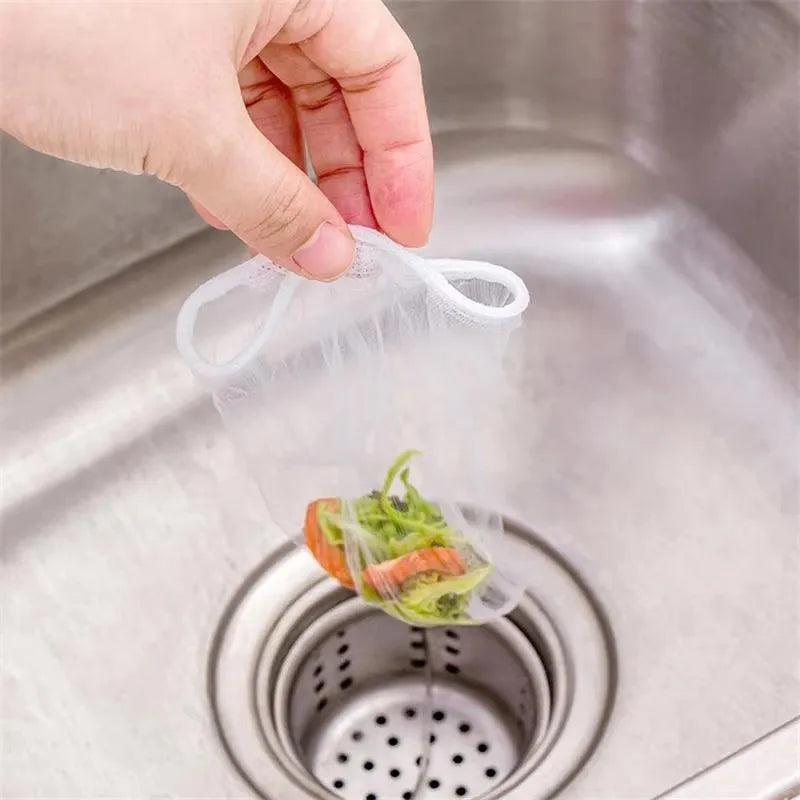 A hand is placing a clear disposable sink drain filter into a metal kitchen sink strainer.