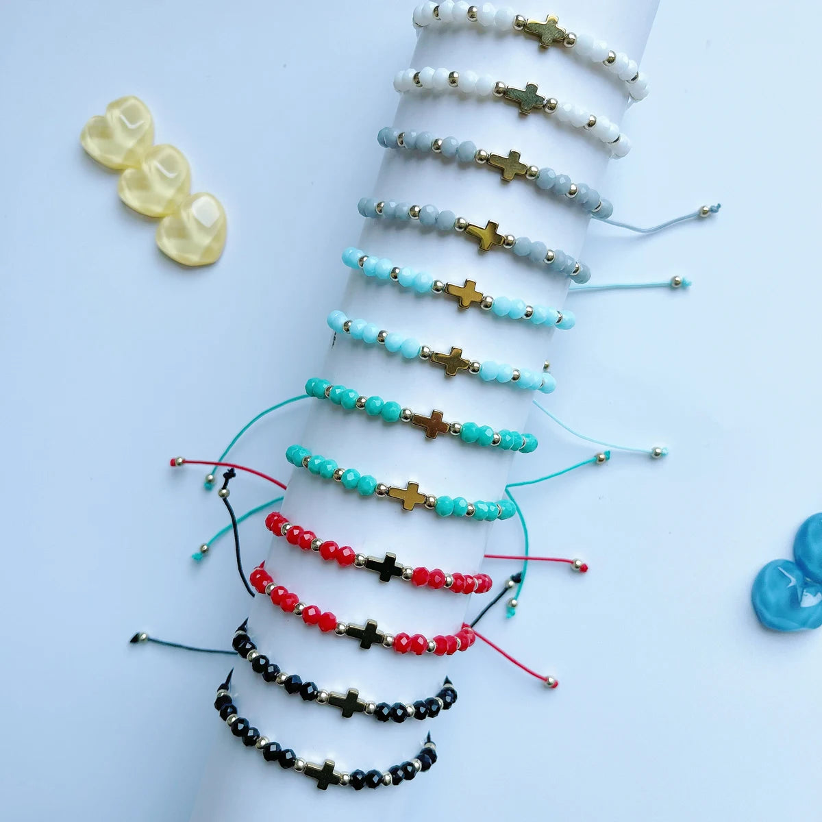 Collection de bracelets en perles bohèmes et croix, empilés verticalement dans différentes nuances de blanc, bleu et rouge.