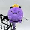 A cute purple plush doll with a yellow crown is displayed in a black wire basket.