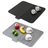 Black silicone dish drying mat with a built-in drain lip and two white mugs placed on it.
