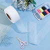 Roll of white no-sew iron-on hem tape next to floral decorations and a small plastic container of colored tapes.