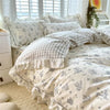 A light gray and white floral ruffle cotton duvet cover set displayed on a bed with sheer window blinds.