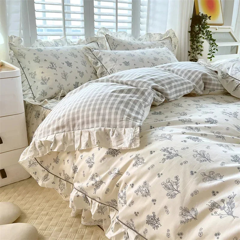 A light gray and white floral ruffle cotton duvet cover set displayed on a bed with sheer window blinds.