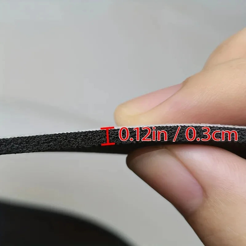 A hand measures the thickness of a black bath mat, showing a dimension of 0.12 inches or 0.3 cm.